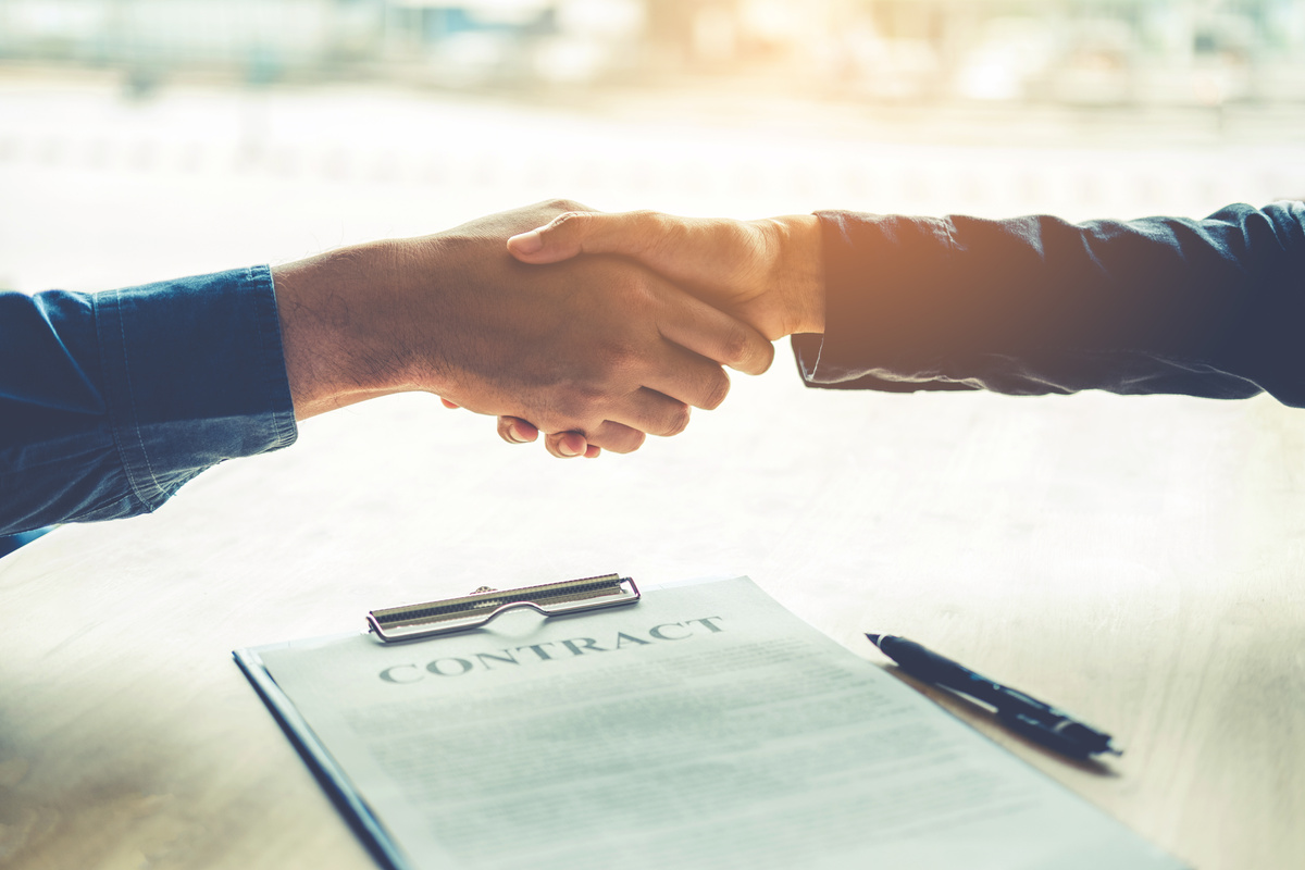 Business people negotiating a contract handshake between two colleagues